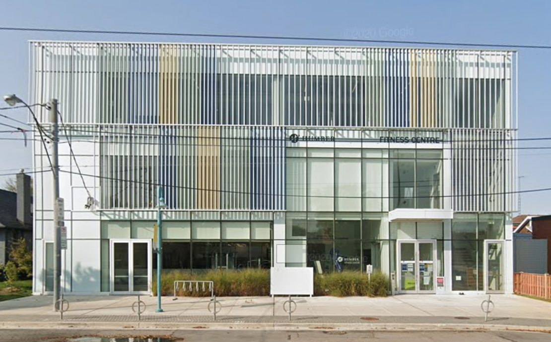 Street view of a white, low-rise building with a glass and steel facade.